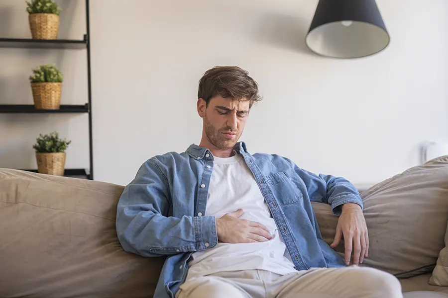 Persona con estrés y problemas digestivos que siente molestias abdominales durante una situación de tensión